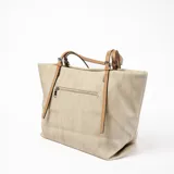 Cartera tipo tote de cuero sintético color beige con bolsillo frontal y correa bandolera ajustable y desmontable.