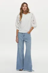 Blusa blanca con mangas abullonadas de broderie, cuello elevado con volados y detalles de volados en los hombros.