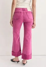 Jean de mezclilla azul oscuro con costuras contrastantes marcadas en el frente y dobladillo ancho vuelto en el ruedo.