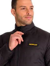 Chaqueta acolchada negra con cierre frontal, cuello alto y parche de silicona con logo Caterpillar en el pecho. Cuenta con aislamiento térmico, es resistente al agua y al viento, con ribetes elásticos en puños y dobladillo.