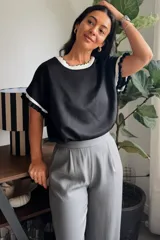 Remera negra de manga corta con detalles en contraste blanco en el cuello redondo y en los puños, con terminaciones onduladas.