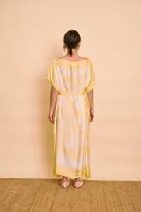 Vestido midi amarillo y blanco con estampado de paisajes y detalles de rayas en el cuello y el dobladillo, de corte holgado, mangas cortas y lazo ajustable en la cintura.