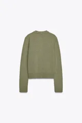 Chaqueta de tejido de punto color verde musgo, de corte cropped, con cuello redondo y cierre frontal de botones oscuros.