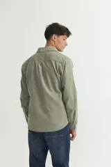 Sobrecamisa verde oliva de pana con cuello solapa, calce holgado, bolsillos con tapa en el pecho y botones personalizados.