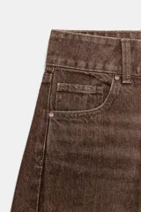 Jeans de tiro medio con diseño wide leg, confeccionados en denim color marrón con efecto lavado. Presentan cinco bolsillos, cierre frontal con cremallera y doble botón metálico.