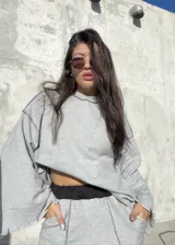 Conjunto deportivo compuesto por un buzo de corte oversize con cuello redondo y costuras expuestas en contraste, y un pantalón de tiro medio con cintura elástica negra y costuras verticales decorativas. Ambas prendas presentan un diseño de bordes desflecados.