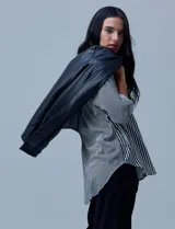 Blazer de eco cuero negro con corte oversized, cuello con solapa, cierre frontal con botones y bolsillos delanteros aplicados.