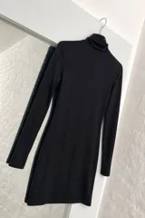 Vestido corto negro de cuello alto y manga larga, con diseño ajustado al cuerpo.