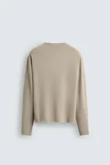 Jersey de manga larga, cuello redondo y calce relajado, color negro con efecto lavado y textura tejida.