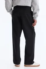Pantalón sastrero color negro de corte relajado, confeccionado en mezcla de algodón y lyocell, con pliegues frontales y bolsillos laterales.