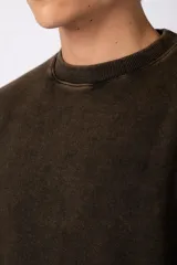 Buzo de cuello redondo con efecto desgastado y lavado vintage en color marrón oscuro. Presenta un calce amplio y cómodo, con puños y ruedo acanalados, y un pequeño logo estampado en la parte inferior frontal.