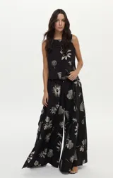 Pantalón palazzo negro con estampado artesanal en tonos claros, cintura elastizada, bolsillos laterales y aberturas en las piernas.