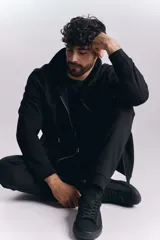 Campera deportiva negra con cierre frontal y capucha con cordones ajustables.