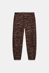 Pantalón de tiro medio con corte barrel, caracterizado por su silueta holgada en cadera y muslos que se estrecha hacia el tobillo. Presenta estampado animal print, bolsillos delanteros y cierre frontal con cremallera, botón y gancho.