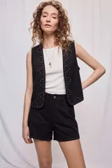 Chaleco negro de efecto gamuza con calce recto, diseño abierto y detalles de tachas metálicas doradas en el frente.