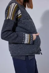 Chaleco tejido de punto color marrón con cuello de piel sintética, cierre frontal con cursor de cuero y diseño acolchado con cortes horizontales.