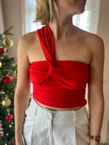 Top negro ajustado al cuerpo, con diseño asimétrico de un solo hombro y detalle de nudo fruncido en el centro del busto.