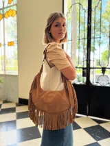 Cartera bandolera de cuero color camel con flecos largos en la parte inferior.