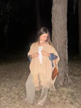 Ruana de lana merino en color champagne, con diseño de tejido de punto y terminación de flecos en el ruedo. Prenda de estilo bohemio y atemporal.