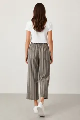 Pantalon de corte holgado y tiro medio, con diseño de rayas verticales en tonos marrones y grises. Cuenta con cintura elástica y bolsillos traseros.