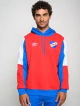 Canguro de felpa Umbro del Club Nacional de Football, con diseño tricolor en rojo, azul y blanco. Presenta capucha con cordones ajustables, bolsillo tipo canguro frontal, logo de la marca y escudo del club bordados en el pecho.