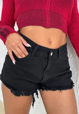 Short de jean negro de tiro alto, con ruedo deshilachado y etiqueta decorativa con texto en el bolsillo trasero.