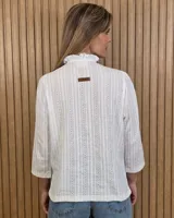 Camisa de algodón color blanco, con cuello alto con volados, mangas tres cuartos con detalles de bordado ingles y cierre frontal con botones de nácar.