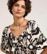 Vestido corto con estampado bicolor de flores y animales, escote corazón, mangas cortas acampanadas y falda con volados. Confeccionado en viscosa texturizada.