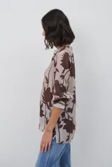 Camisa de manga larga con estampado floral en tonos marrones y negros, cuello mao y cierre frontal parcial con botones.