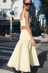 Falda de tiro medio color amarillo claro, confeccionada en tejido de punto elástico con detalle de aplicación combinada y bajo en línea evasé. Cuenta con cierre lateral con cremallera oculta.