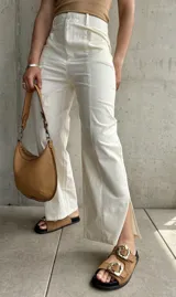 Pantalón de lino color crudo, de corte recto, con pinzas en la cintura y aberturas laterales en el ruedo.