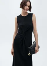 Vestido midi negro sin mangas, confeccionado en algodón, con cuello redondo y diseño recto. Presenta detalles drapeados con un nudo en el centro de la cintura.