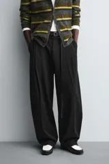 Pantalón de corte balloon fit en color gris, confeccionado en tejido con viscosa. Presenta pliegues frontales, cintura con cinturón integrado a contraste, bolsillos laterales y bolsillos traseros de vivo.
