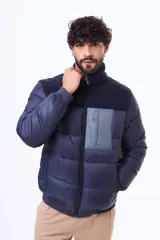 Campera puffer negra con paneles de textura tipo corderito en la parte superior del pecho y hombros. Cuenta con cierre frontal, puños y ruedo acanalados, y un bolsillo vertical con cierre en el pecho.