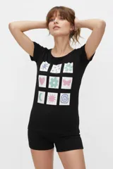 Remera de manga corta color negro, con cuello redondo y diseño holgado. Cuenta con un estampado frontal compuesto por una cuadrícula de nueve recuadros blancos con diversos símbolos coloridos en tonos pastel.