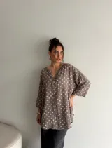 Blusa de viscosa con estampado de lunares, corte holgado, mangas tres cuartos y escote en V con botón central.