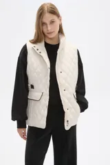 Chaleco acolchado de diseño capitoneado en color verde militar, con cuello alto, cierre frontal con botones a presión y bolsillos laterales con solapa y detalles en contraste.