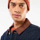 Chaqueta de denim azul oscuro con cuello de pana en color marrón, cierre frontal con botones metálicos, bolsillos frontales tipo parche y costuras a contraste.