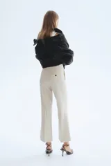 Pantalón tobillero de corte bootcut, color beige, con cintura estándar, raya marcada al frente y en la espalda, y cierre con pretina prolongada y botón.