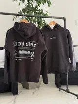 Canguro negro oversize de felpa, con capucha, bolsillo tipo canguro y diseño estampado en la espalda con gráficos estilo streetwear y texto en blanco.
