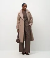 Pantalón de vestir estilo sastre con corte wide leg, confeccionado en tejido crepé color marrón con sutil estampado de rayas verticales. Presenta pliegues delanteros, cintura estructurada con trabillas y cierre frontal.