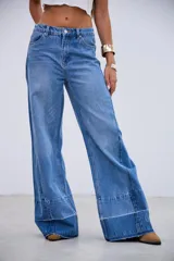 Jean de corte wide leg con tiro medio, confeccionado en denim rígido sin elastano. Presenta un diseño de paneles con costuras verticales y un ruedo con detalle de costura horizontal y terminación desflecada.