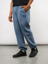 Pantalón de jogging Umbro modelo Northbound, confeccionado en tejido de felpa con friza. Presenta un diseño holgado con puños elásticos en los tobillos, bolsillos laterales y logo de la marca bordado en un parche cuadrado en el muslo.