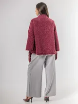 Chaqueta tipo capa de textura peluda en color bordó, con cuello mao y cierre frontal con botones grandes.