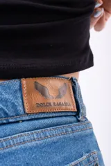Pantalón de jean estilo wide leg, de tiro alto con cierre frontal de botones a la vista. Confeccionado en denim rígido de corte recto y holgado.