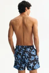 Short de baño azul marino con estampado de peces, estrellas de mar y caracolas en tonos azules y blancos. Cuenta con cintura elástica con cordón de ajuste.