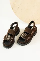 Sandalias negras de cuero con diseño de plataforma dentada, tiras ajustables con hebillas metálicas y detalle de tachas plateadas en el lateral de la suela.