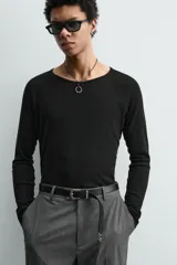 Camiseta negra de corte relaxed fit, confeccionada en tejido ligero con algodón. Presenta cuello redondo y manga ranglán larga.