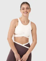 Top deportivo blanco con escote redondo y bandas elásticas cruzadas bajo el busto, con abertura en la espalda.