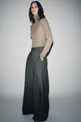 Pantalón de tiro medio con corte wide leg, confeccionado en tejido con viscosa y diseño de raya diplomática. Presenta pinzas frontales, bolsillos laterales ocultos y cierre frontal con cremallera, botón y ganchos metálicos.